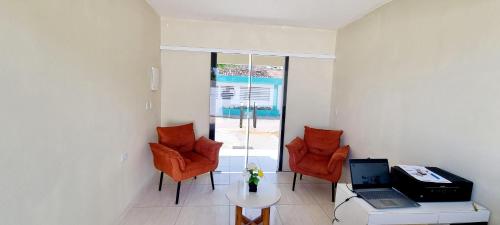 a living room with orange chairs and a table with a laptop at Pousada Peromar in Maragogi