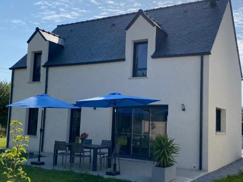 two blue umbrellas and tables in front of a house at Maison de vacances à Sarzeau à 5 min de la plage à pieds in Sarzeau