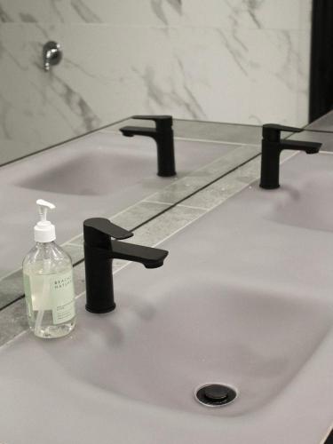 a bathroom sink with a bottle of soap on it at Large Modern 3BR 2 BATH Apt in Central Location for Families, Workers, Groups in Fyshwick