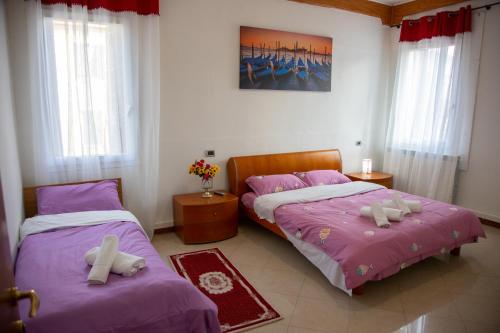 2 camas en una habitación con sábanas moradas y almohadas blancas en BB CA VENEZIA en Marghera