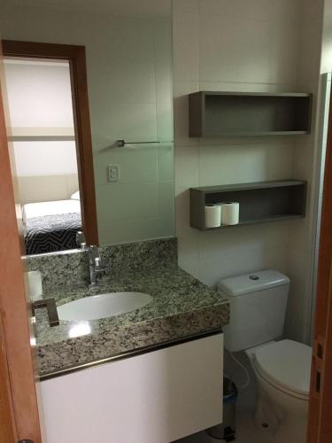 a bathroom with a sink and a toilet and a mirror at Itacimirim Apartments Boulevard e Ondas in Itacimirim