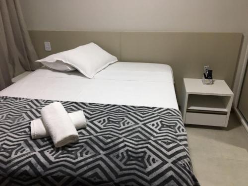 a bedroom with a bed with a black and white comforter at Itacimirim Apartments Boulevard e Ondas in Itacimirim