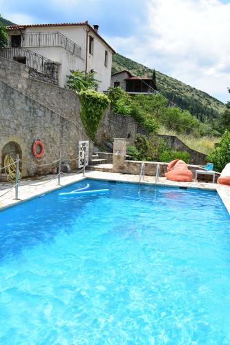 a large blue swimming pool in front of a building at Kyriaki Guesthouse & Suites in Amfiklia