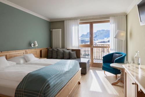 um quarto de hotel com uma cama e um sofá em ICARO Hotel em Alpe di Siusi