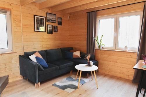 a living room with a black couch and a table at Domek letniskowy Letniczówka in Warchały
