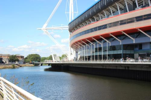 a bridge over a river next to a building at 1 Fitzhamon Embankment APARTMENTS opposite Principality Stadium - LONG STAY OFFER in Cardiff