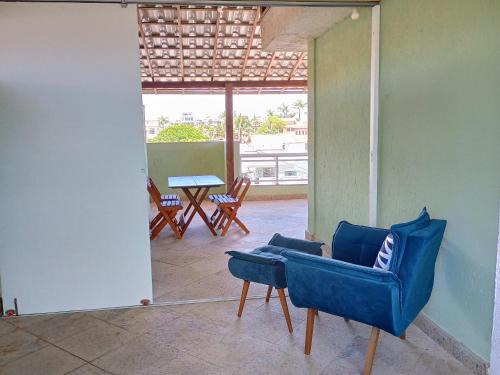 a living room with a blue chair and a table at Triplex 3 quartos a 100 metros de Costa Azul in Rio das Ostras