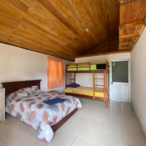 1 dormitorio con cama y techo de madera en Cabañas Barú, en Tena