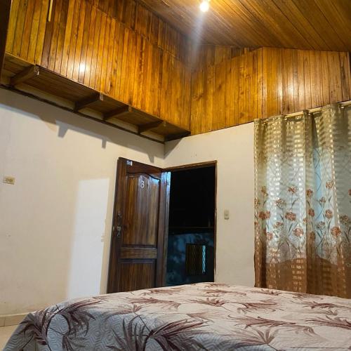 1 dormitorio con cama y techo de madera en Cabañas Barú, en Tena