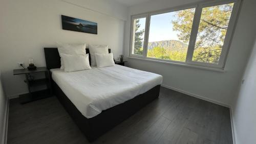 a bedroom with a bed with white sheets and two windows at Комплекс Маджарово in Madzharovo