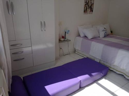 Kleines Zimmer mit einem lila Bett und einem Schrank in der Unterkunft Vista Mar - Studio em Copacabana a 1 min da praia e próximo ao metrô in Rio de Janeiro