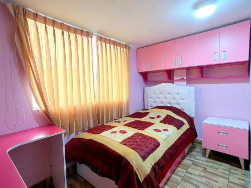 Habitación pequeña de color rosa con cama y armarios rosados en Apartamento en El Tambo - Huancayo, en Huancayo