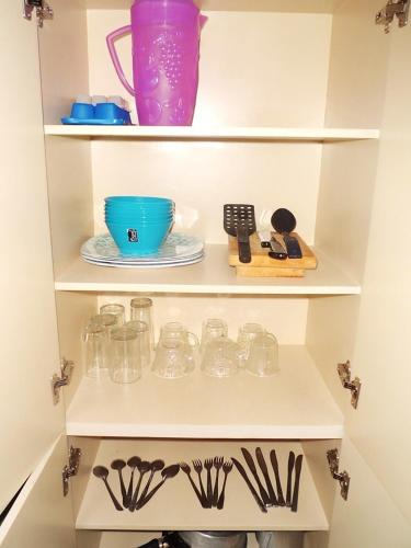 a white cabinet with dishes and utensils in it at Suites Angelopolis in Acapulco
