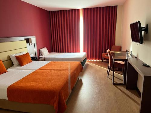 Habitación de hotel con 2 camas y escritorio en Palace Hotel & SPA Termas do Bicanho, en Soure