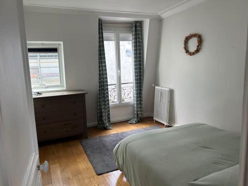 une chambre avec un lit, une commode et une fenêtre dans l'établissement Appartement sur les toits de Paris vue Tour Eiffel 4 chambres, à Paris