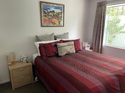 Un dormitorio con una cama con sábanas rojas y una ventana en Villa55, en Christchurch