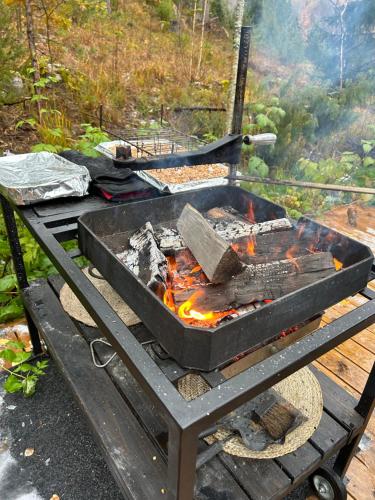 a grill on a wooden table with fire in it at Sauna cabin in the heart of Nuuksio National Park in Espoo