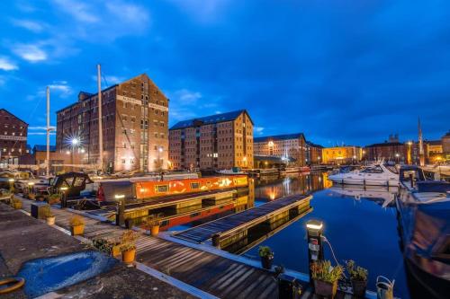 a marina at night with buildings and boats in the water at Stylish Ground Floor Apartment Nr Gloucester Docks, by Sauvignon Stays 