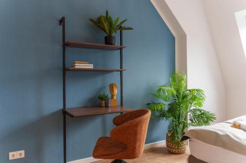 Un dormitorio con una pared azul con una silla y estanterías en BENVILLE Freital - WLAN - Nespresso Kaffee - Windbergblick, en Freital