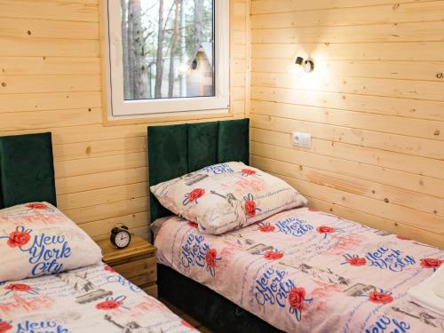 two beds in a room with wooden walls at Aura Zawady in Popów