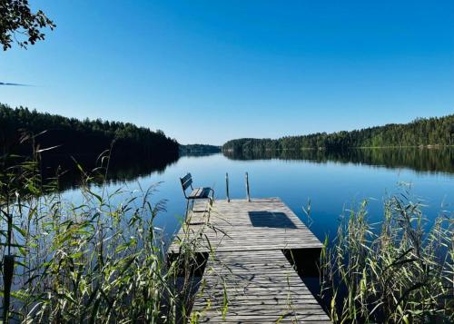 a chair sitting on a dock on a lake at Sauna cabin in the heart of Nuuksio National Park - Mökki Nuuksiossa in Espoo