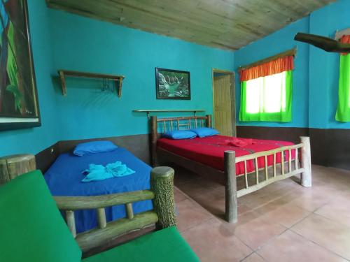 2 camas en una habitación con paredes azules en Reserva Natural Cañón Seacacar, en Izabal