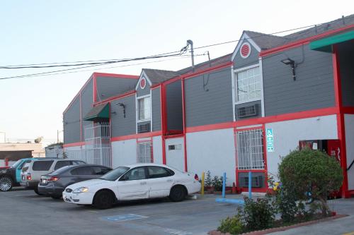 a white car parked in a parking lot next to a building at The Broadway Inn in Los Angeles