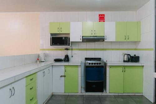 - une cuisine avec des placards verts et blancs et une cuisinière dans l'établissement MODERNO DEPARTAMENTO CON 4 HABITACIONES, à Huancayo