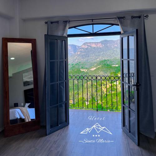 a bedroom with a door open to a balcony with a view at Hotel Santa María in Taxco de Alarcón