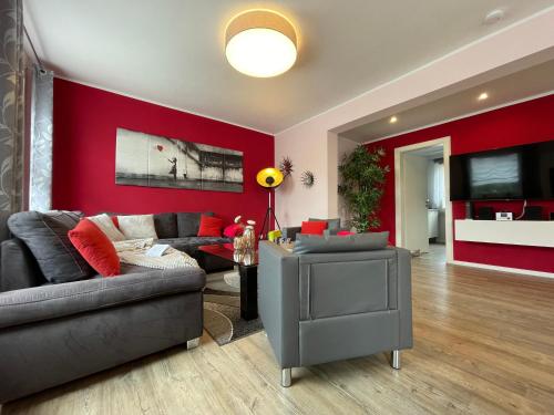 a living room with a couch and a red wall at Ferienhaus BellaVita - mit großem eingezäuntem Garten - Infrarotsauna - 3 Hunde willkommen - Badesee 800m entfernt in Walkenried