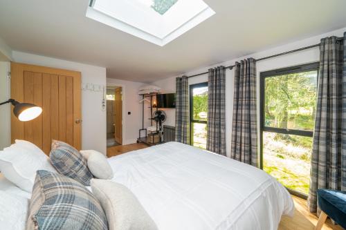 a bedroom with a large white bed and a window at Rowanbank Cabin - a gorgeous country escape in Kirkton of Auchterhouse
