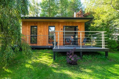 a small wooden cabin with a porch in the grass at Rowanbank Cabin - a gorgeous country escape in Kirkton of Auchterhouse