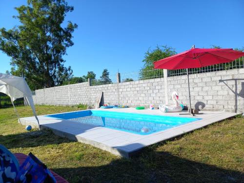 a swimming pool with a red umbrella and an umbrella at El Descanso Silletano in La Silleta