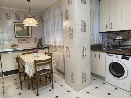 a kitchen with a table and a washing machine at Elegante apartamento con vistas al puerto de Santander in Santander