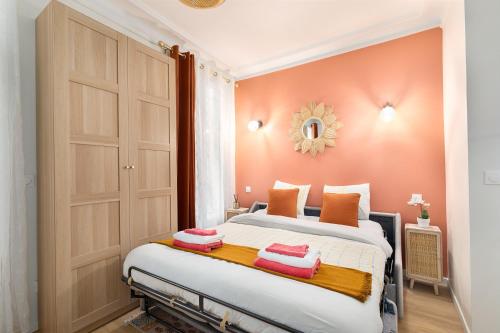 a bedroom with a large bed with orange walls at Guestrust- Arc de Triomphe Corail in Paris