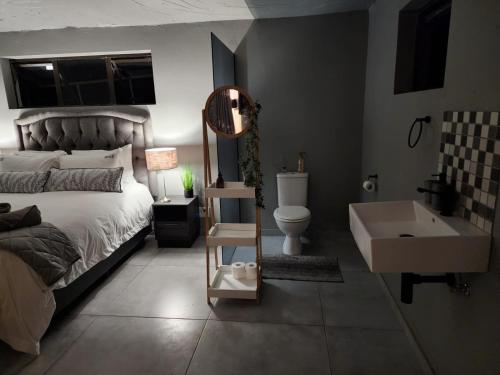 a bedroom with a bed and a tub and a sink at Gecko Lodge and Cottage, Mabalingwe in Warmbaths