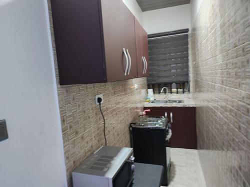 een kleine keuken met bruine kasten en een magnetron bij Commander Place Accra-Urban Budget Living 1,2-Beds in Oyarifa, Wifi, 5star service, 35mins to airport, by DLA in Oyarifa
