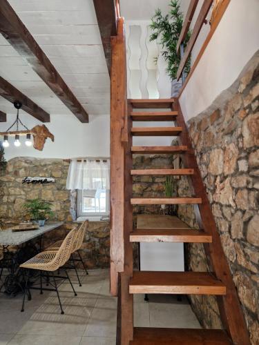 escalera de madera en una habitación con pared de piedra en Holiday House VUKI, en Nedeščina