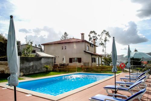 einen Pool mit Stühlen und Sonnenschirmen vor einem Haus in der Unterkunft Martins House in Vila Viçosa