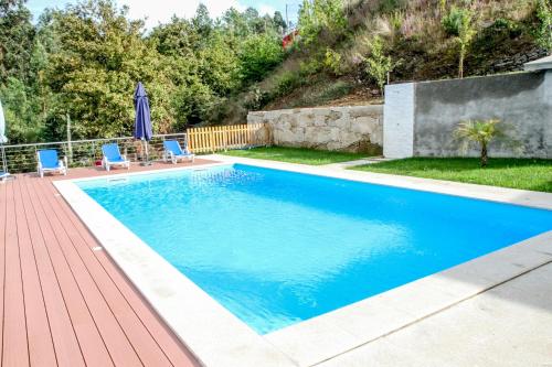 einen Pool mit zwei blauen Stühlen auf einer Holzterrasse in der Unterkunft Martins House in Vila Viçosa