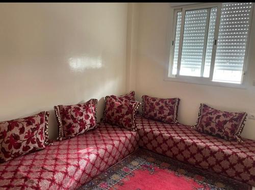 Sofá rojo sentado en una habitación con ventana en Magnifique appartement à Bouznika en Bouznika