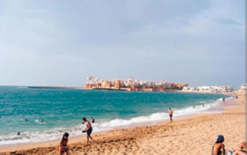un grupo de personas en una playa con el océano en Magnifique appartement à Bouznika en Bouznika
