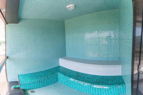 La salle de bains est pourvue d'une douche carrelée de bleu et d'une baignoire. dans l'établissement Apartamento com Vista Deslumbrante à Beira Mar., à Récife