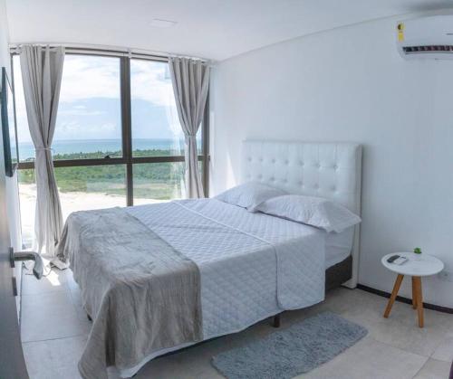 - une chambre blanche avec un lit et une grande fenêtre dans l'établissement Apartamento com Vista Deslumbrante à Beira Mar., à Récife