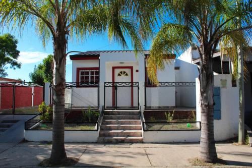 a white house with palm trees in front of it at Hospedaje BAHUINIAS II in Federación