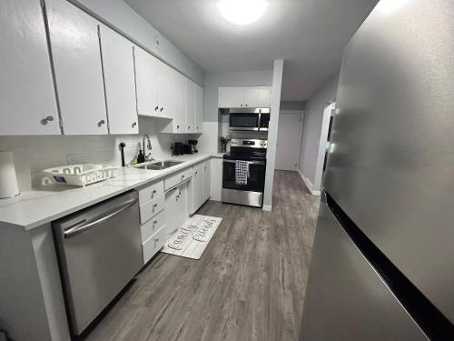 a kitchen with white cabinets and a stainless steel refrigerator at Cute Highland Park Entire Unit A in Calgary