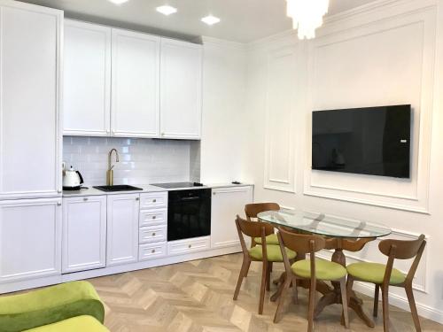 una cucina con armadi bianchi, tavolo e sedie di Brand new 1-bedroom apartment in city centre a Gori