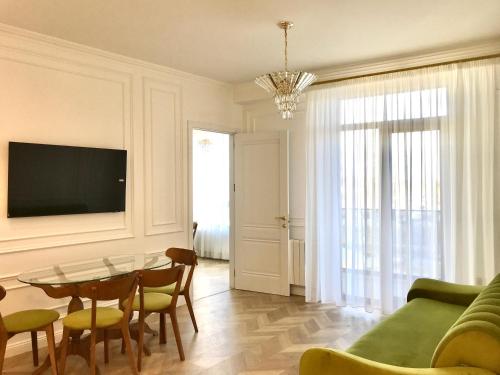 un soggiorno con tavolo, sedie e TV di Brand new 1-bedroom apartment in city centre a Gori