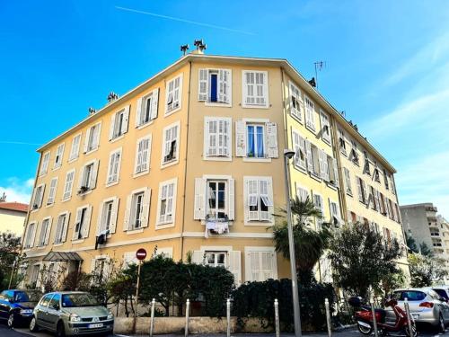un bâtiment jaune avec des voitures garées devant dans l'établissement Lumineux appartement deux pièces, à Nice
