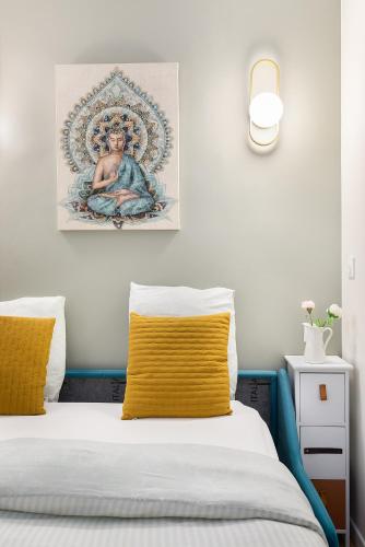 - un lit avec un oreiller jaune et une peinture sur le mur dans l'établissement Guestrust - Arc de Triomphe Green, à Paris